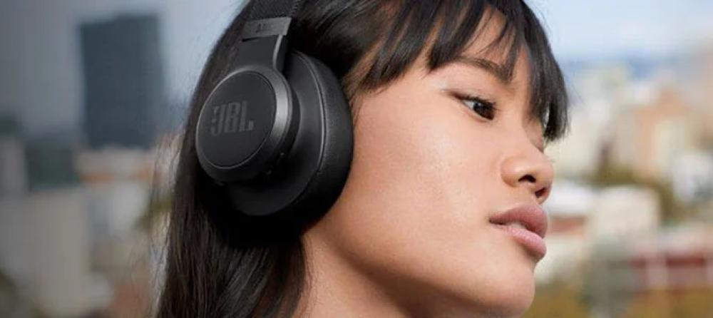 Young woman listening to music with JBL portable Bluetooth speaker outdoors